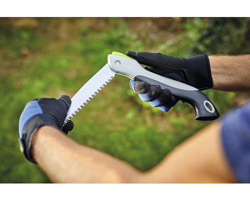 Osoba drží skládací pilu s rukavicemi.