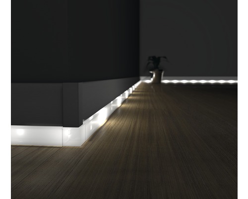 Scéna s nepřímým osvětlením pomocí LED pásků podél tmavé stěny a dřevěné podlahy