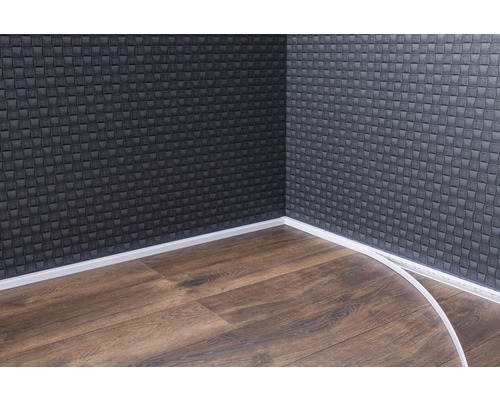 Roh místnosti s tmavým obkladem stěn, laminátovou podlahou a bílými podlahovými lištami