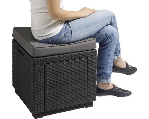 Osoba sedí na úložném boxu z ratanu se sedákem