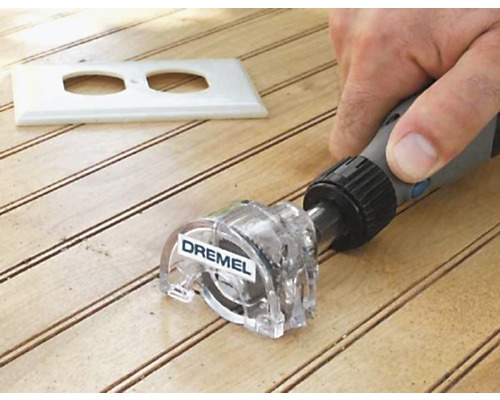 Frézovací nástavec Dremel používaný na dřevěném povrchu s výřezem pro zásuvku