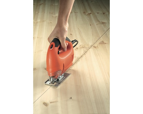 Osoba řeže dřevěnou desku podél čáry pomocí přímočaré pily.