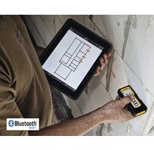 Osoba měří zeď laserovým dálkoměrem a zároveň se dívá na tablet s půdorysem.