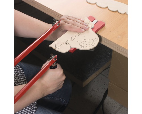 Osoba řeže tvar dinosaura lupénkovou pilou