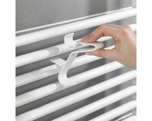 Ruka připevňuje háček na ručníky k radiátoru