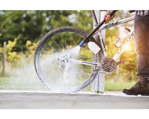 Osoba čistí jízdní kolo vysokotlakým čističem.