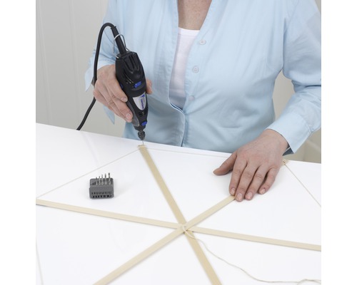 Osoba vrtá dřevěný model multifunkčním nástrojem Dremel.