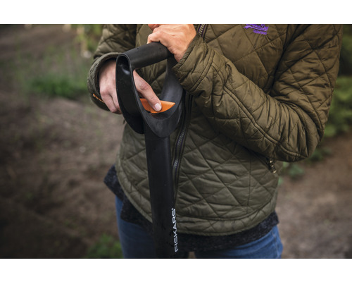 Osoba s rýčem Fiskars na zahradě