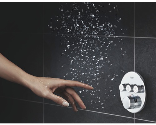 Sprcha s ovládacím prvkem a rukou pod proudem vody na tmavém pozadí