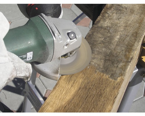 Osoba brousí kus dřeva úhlovou bruskou.