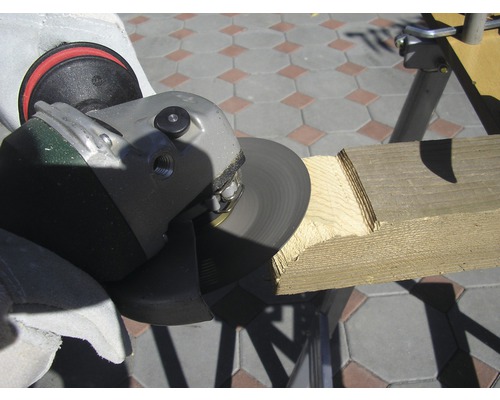 Osoba používá úhlovou brusku k opracování kusu dřeva.