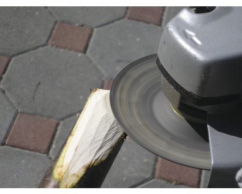 Úhlová bruska opracovává kus dřeva.