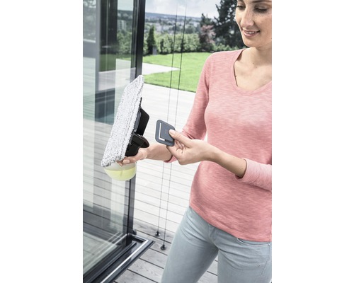 Žena čistí skleněnou tabuli čističem oken.