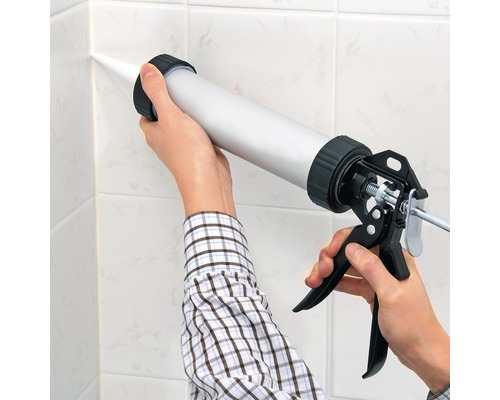 Nanášení tmelu pomocí aplikační pistole na dlaždice