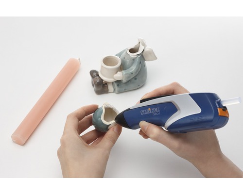 Osoba opravuje keramickou figurku tavnou pistolí Steinel.