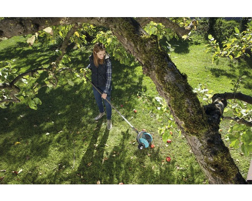 Žena používá sběrač ovoce v zahradě pod stromem.