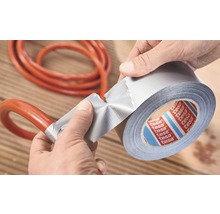 Osoba opravuje hadici lepicí páskou. Logo Tesa.