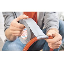 Osoba opravuje hadici lepicí páskou