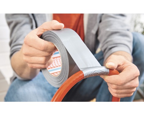 Osoba opravuje hadici lepicí páskou