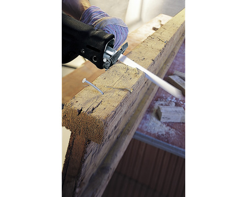 Přímočará pila řeže dřevěnou desku s hřebíky.