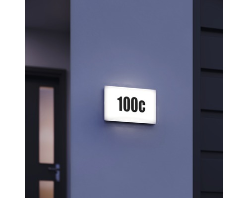 Osvětlená tabulka s číslem domu s číslem 100c na zdi