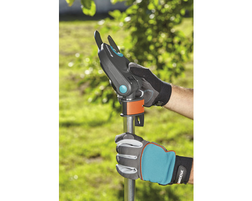 Zahradní nůžky s násadou v použití, držené zahradními rukavicemi.