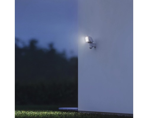 Venkovní nástěnné svítidlo s pohybovým senzorem osvětluje stěnu domu v noci.