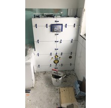 Renovace koupelny s bílými obklady na stěně a nářadím