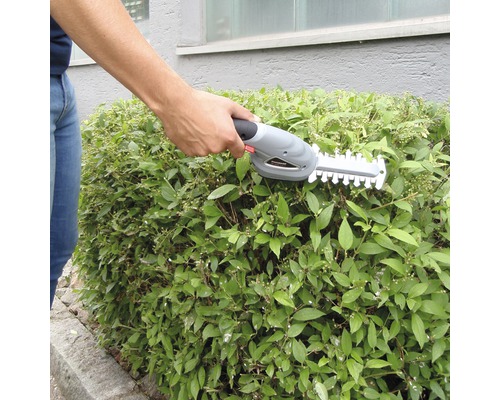 Osoba stříhá živý plot akumulátorovými nůžkami na živý plot