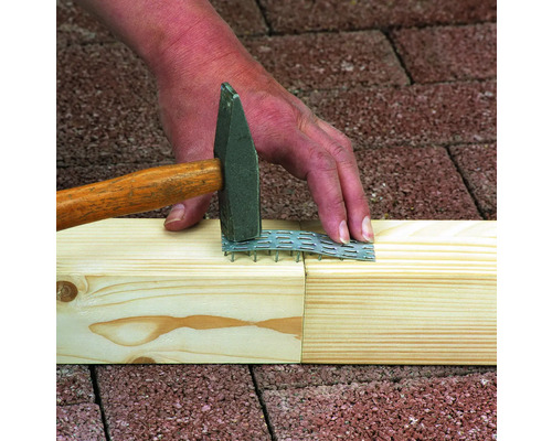 Řemeslník upevňuje dřevo kladivem a hřebíkovou deskou