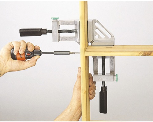 Dvě rohové svěrky fixují dřevo během šroubování šroubovákem.