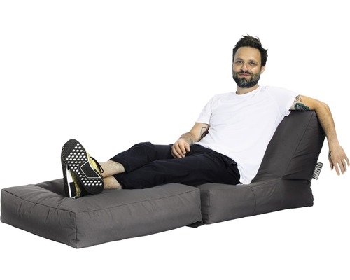 Muž odpočívá na šedém sedacím vaku s podnožkou