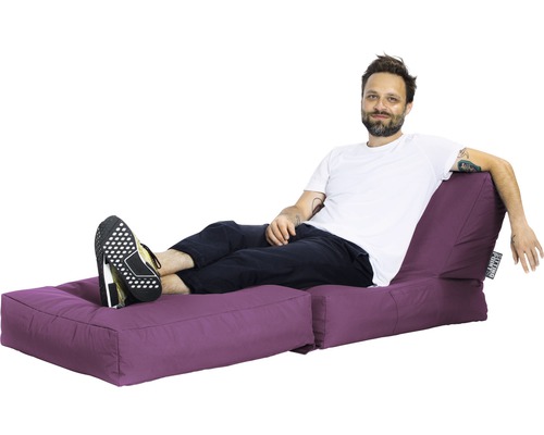 Muž relaxuje na fialovém sedacím ostrově s podnožkou.