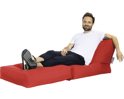 Muž odpočívá na červeném sedacím vaku s podnožkou