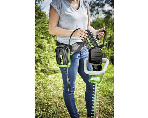 Žena vyměňuje baterii na nůžkách na živý plot s akumulátorovým pásem