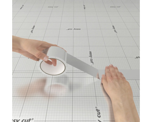 Role lepicí pásky se rozvíjí na řezací podložce.