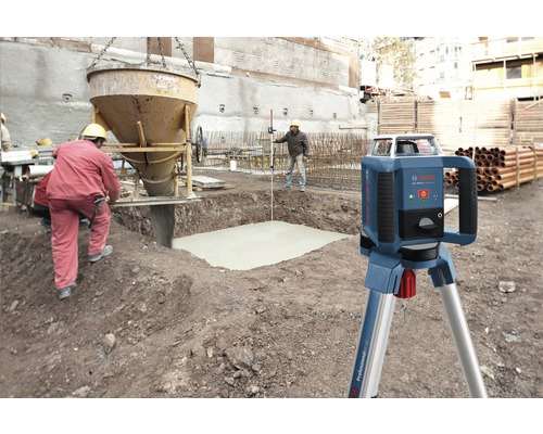 Rotační laser na staveništi s betonářskými pracemi a stavebními dělníky