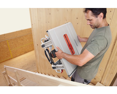 Muž nese stolní okružní pilu Bosch na schodech.