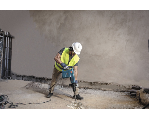 Stavební dělník používá demoliční kladivo k úpravě podlahy.