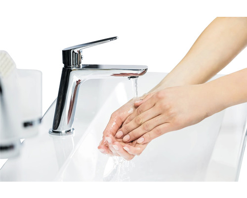 Žena si myje ruce pod kohoutkem v umyvadle