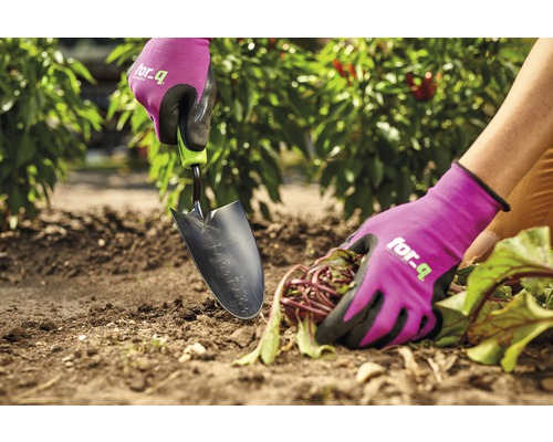 Detailní záběr osoby pracující na zahradě se zahradní lopatkou a zahradními rukavicemi