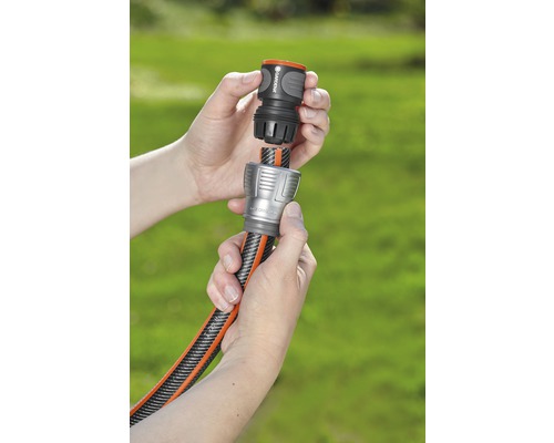 Dvě ruce spojují zahradní hadici se spojkou.