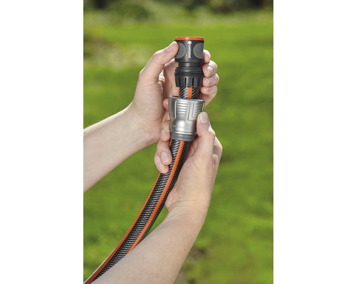 Dvě ruce spojují zahradní hadici s konektorem hadice.