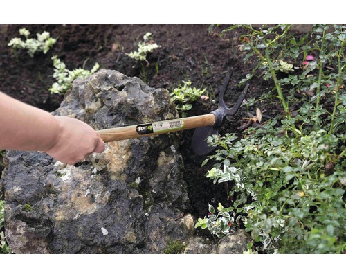 Zahradní motyka s dřevěnou rukojetí používaná v zahradním záhonu.