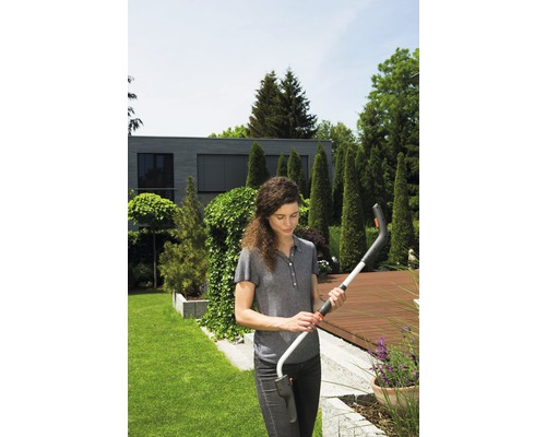 Žena drží akumulátorové nůžky na trávu na zahradě.