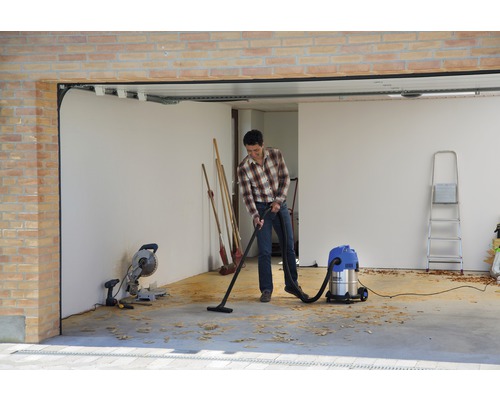 Muž vysává garáž víceúčelovým vysavačem