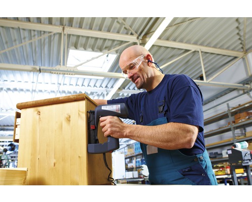 Řemeslník upevňuje dřevo elektrickou sponkovačkou