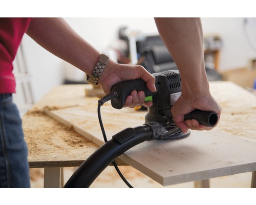 Osoba brousí dřevěnou desku excentrickou bruskou.