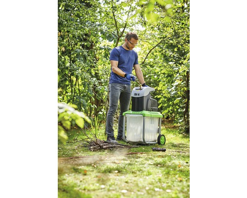 Muž používá zahradní drtič na zahradě.