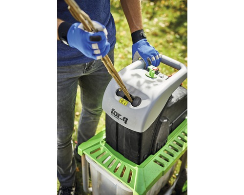 Osoba vkládá větve do drtiče značky for_q.